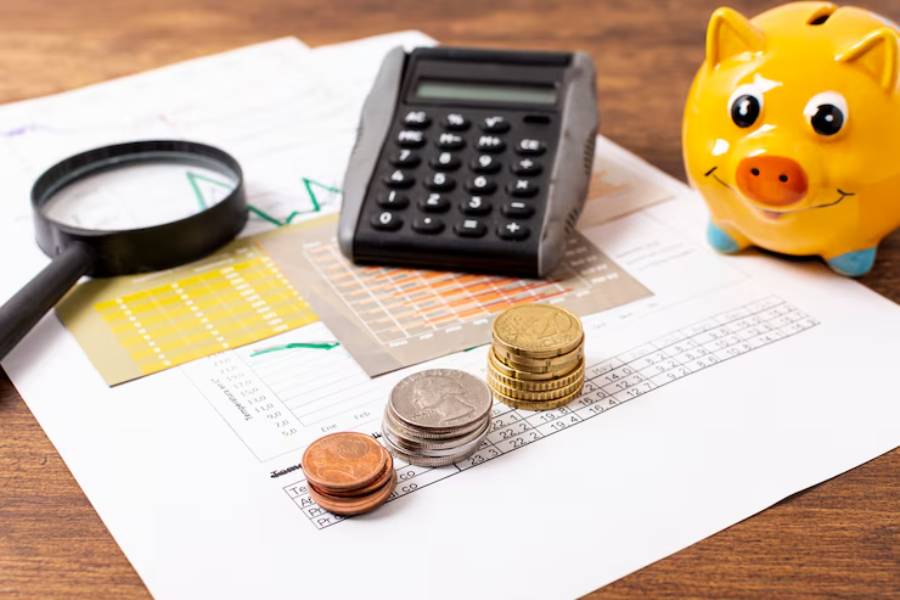 Calculator, coins, and a piggy bank on financial documents with charts, symbolizing personal finance management and savings.